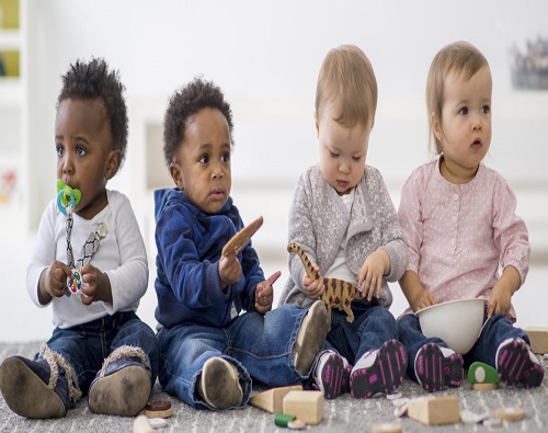 A multi-ethnic group of toddlers are sitting on the floor and are playing together with toys while on a play date.